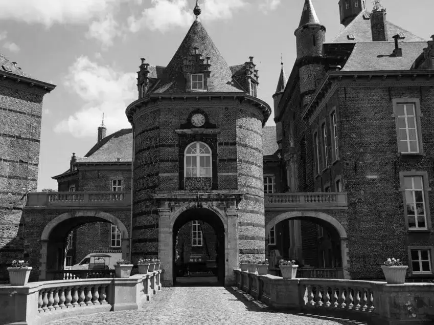 Historisch kasteel met robuuste bakstenen torens, gewelfde doorgang, natuurstenen brug en monumentale architectuur, onderdeel van een erfgoedonderhouds‑ en restauratieproject.