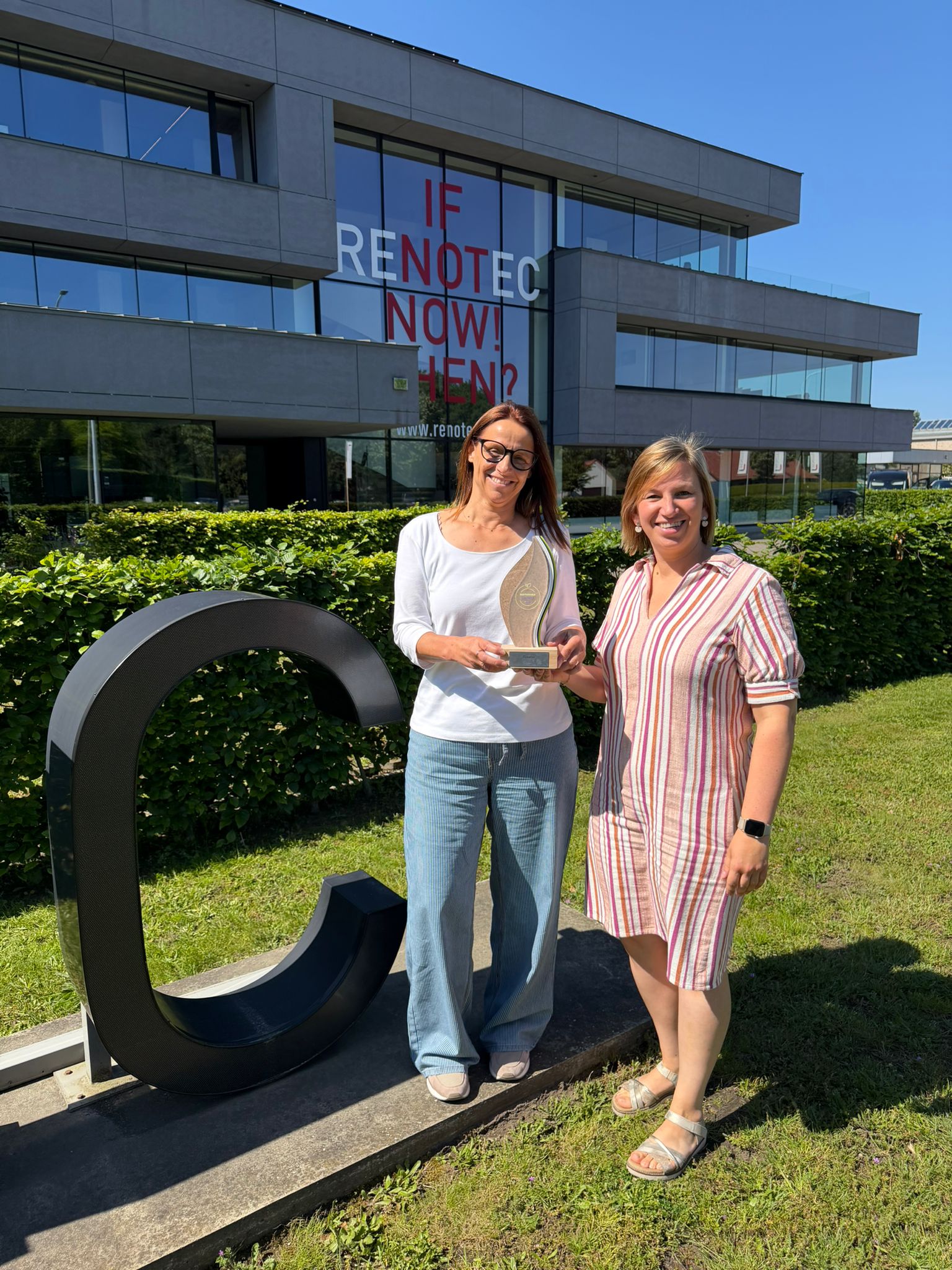 Medewerkers van Renotec tonen een duurzaamheidsaward voor het hoofdkantoor in Geel, als erkenning voor duurzame bedrijfsvoering en ESG-inspanningen.