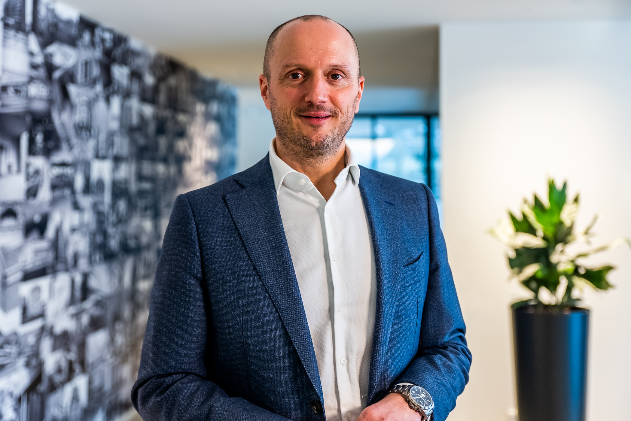 De CEO van Renotec poseert voor een fotowand in een kantooromgeving
