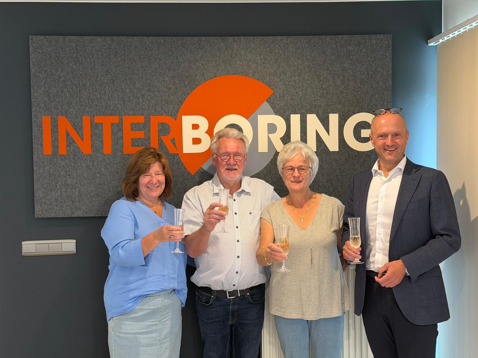 Vertegenwoordigers van Renotec en Interboring poseren voor het Interboring-logo na het tekenen van de overeenkomst van de overname.